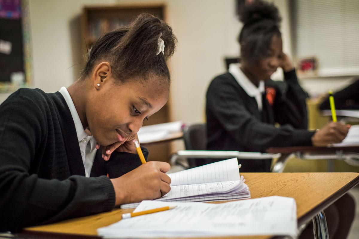 Two African American middle school girls writing at their desks