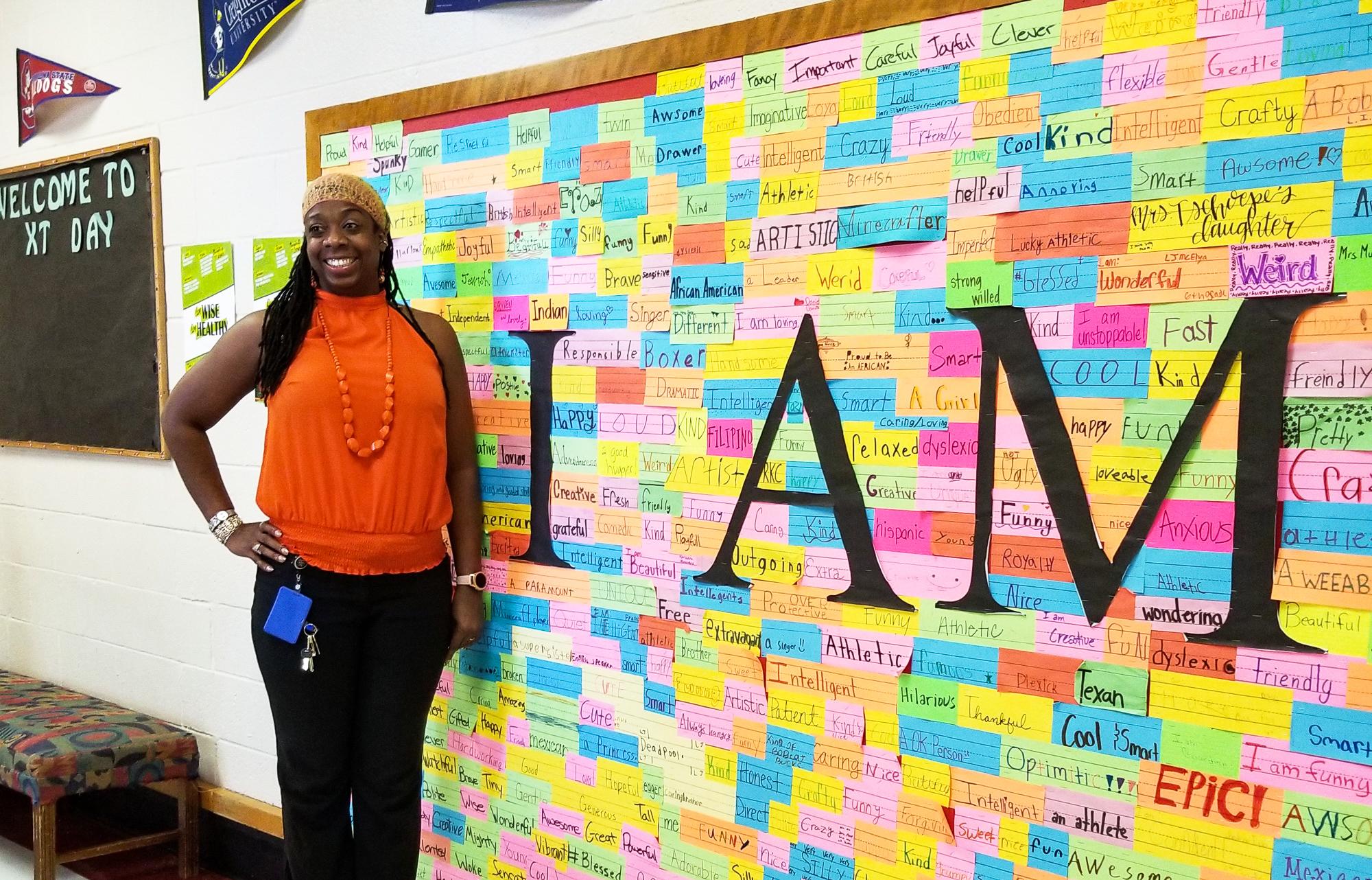 Ta-Tanisha in front of an inspiring bulletin board