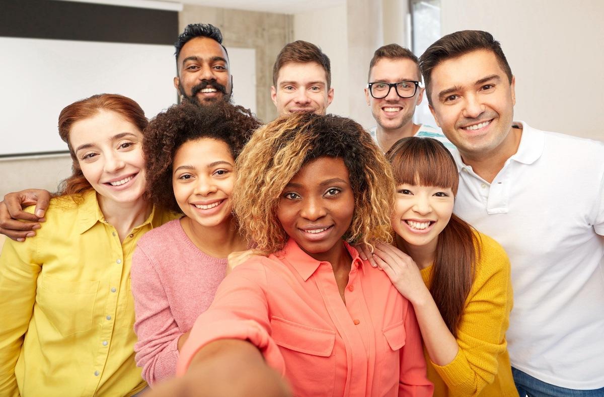 A group of eight diverse future Dallas teachers gather for a group selfie. The person closest to the front holds out the camera in front of her to take the picture.